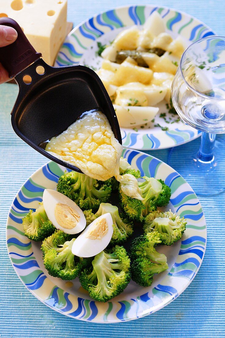 Putting melted raclette cheese on top of vegetables