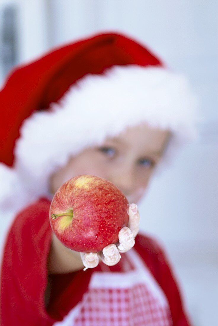 'Young baker' with floury hands holding an apple