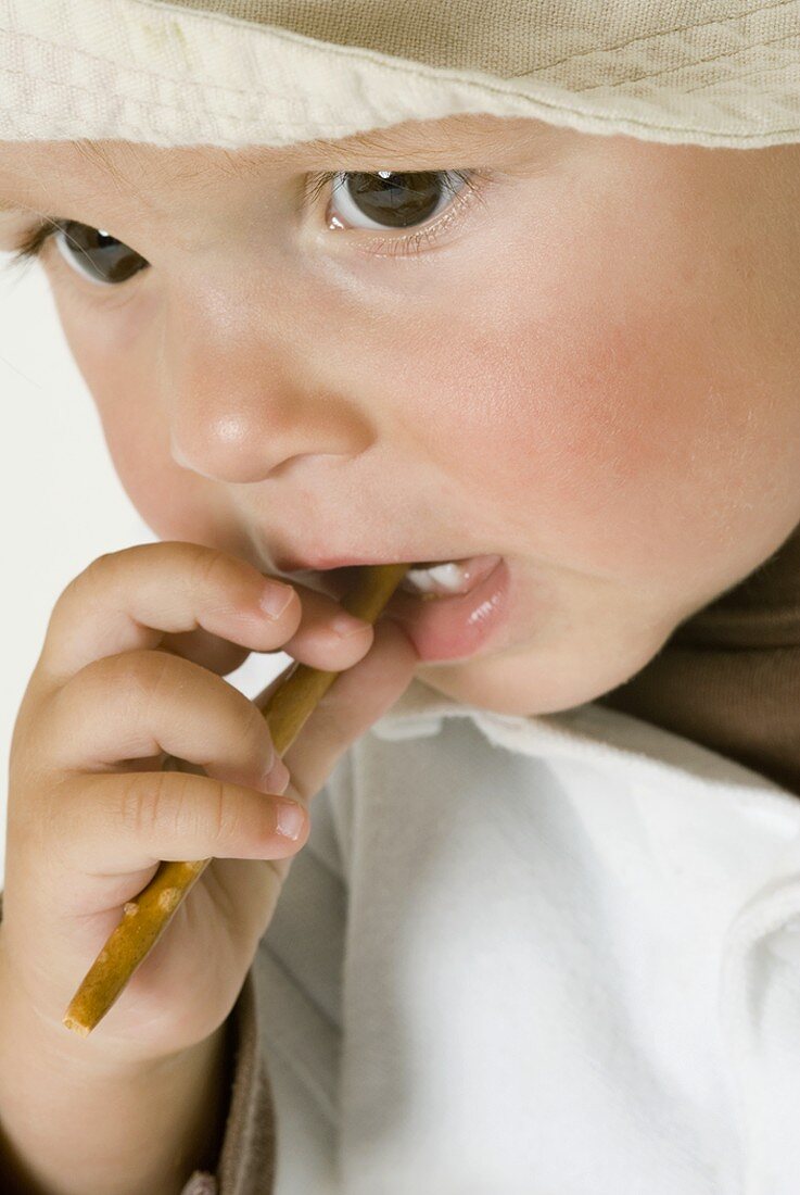 Small boy biting into a salted stick