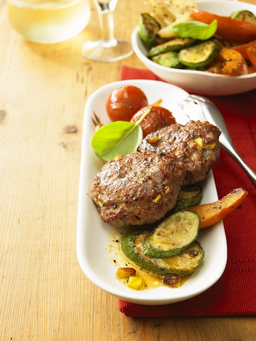 Meat patties with sweetcorn on roasted vegetables