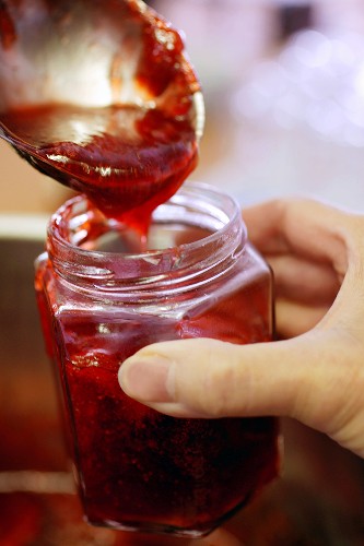 Pouring strawberry jam into jar
