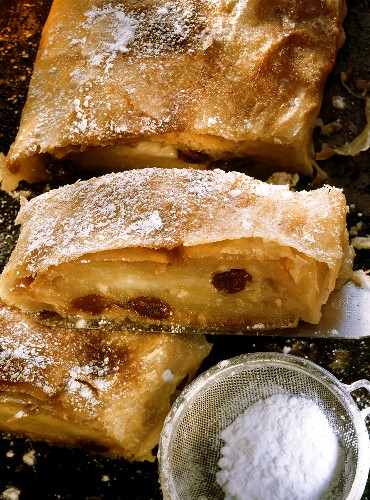 Apple strudel with icing sugar on a baking tray