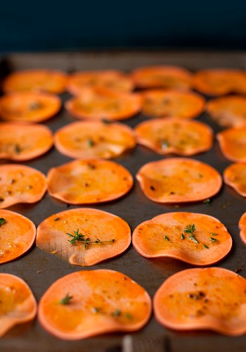 Sliced Sweet Potatoes with Herbs on a Baking Sheet