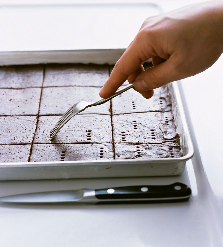 Chocolate shortbread dough being pricked with a fork