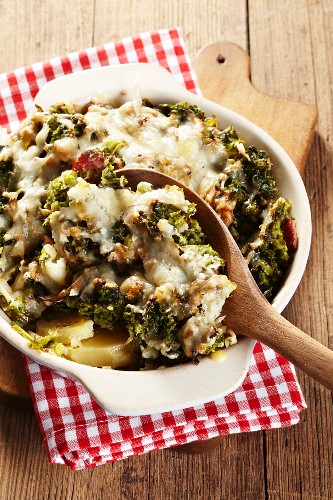Kale bake with a wooden spoon in a baking dish on a red and white checked napkin