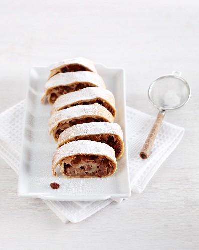 A sliced apple strudel dusted with icing sugar