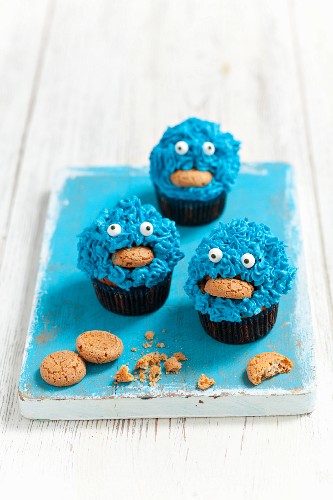 Monster muffins decorated with blue cream and almond biscuits