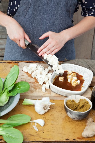 Diced tofu being placed in a marinade