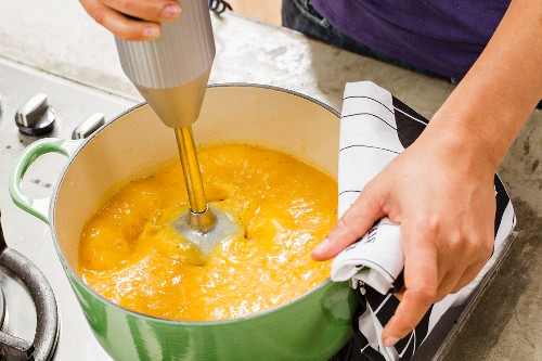 Pumpkin soup being puréed in a pot