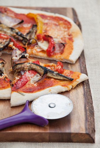 A vegetable pizza with peppers, aubergines and onions, sliced