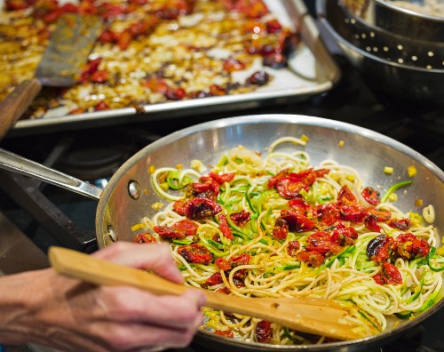 Glutenfreie Spaghetti mit Zucchinispaghetti und gebratenen Traubentomaten in einer Pfanne
