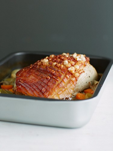 Crispy roast pork with vegetables in a roasting tin