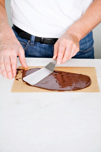 Chocolate leaves being made: liquid chocolate being spread on baking paper