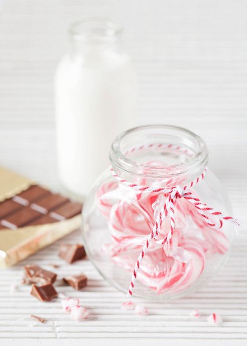 A bottle of milk, a bar of chocolate and candy canes in a sweetie jar