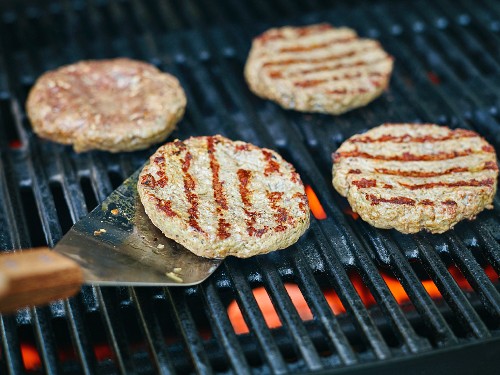 Minced meat steaks being turned on a barbecue