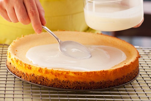 California Cheesecake mit Sauerrahmglasur bestreichen