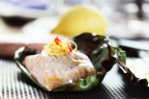 Grilled sturgeon with lemon zest wrapped in a banana leaf