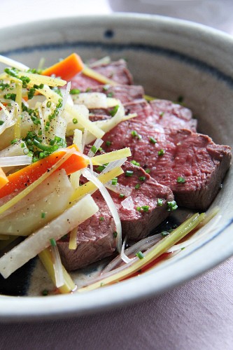 Beef, root vegetables, chives, salt and pepper in a soup dish