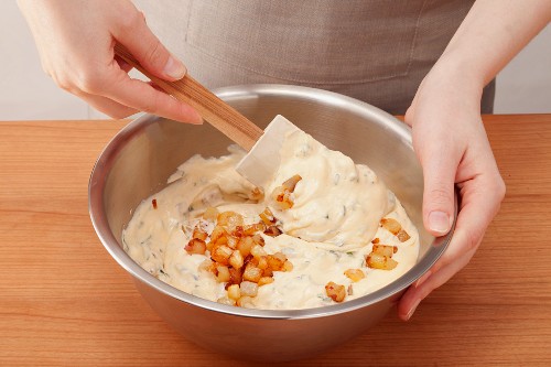 Cream cheese being mixed with pineapple and potato pieces