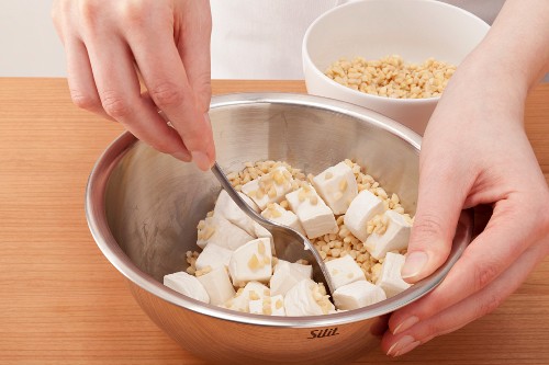 Goat's cheese being mixed with almonds