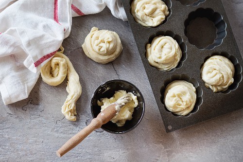 Teig für Cruffins in Silikon-Backformund Butter in einem Schälchen