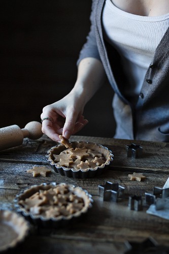 Frau dekoriert Tartelettes mit Gebäcksternen