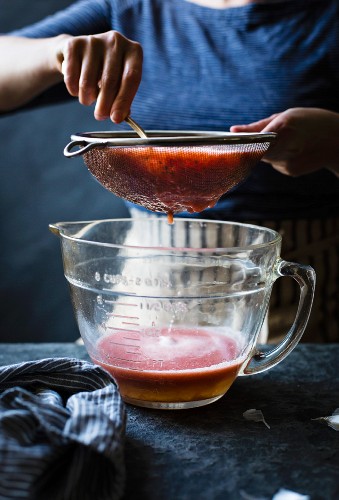 Seiving tomatoes over a measuring jug