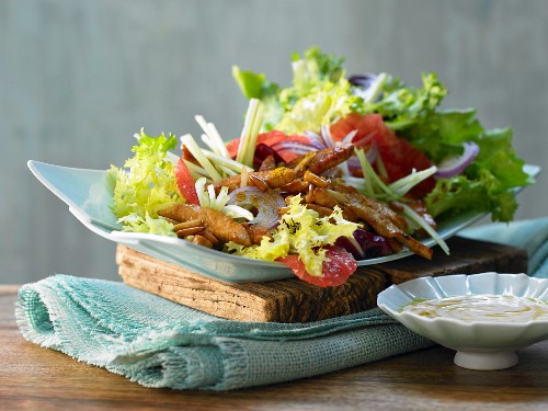 Putenstreifen auf buntem Salat mit Pinienkernen und Grapefruitsauce