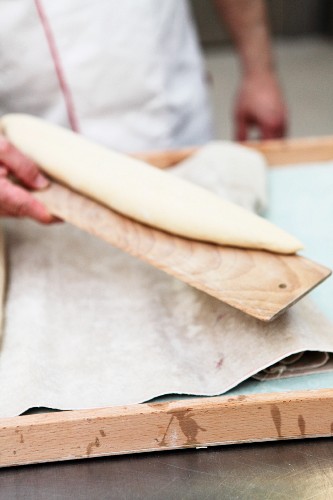 Unbaked French baguette on a wooden board