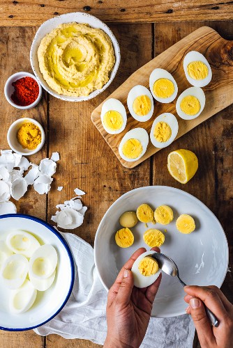 A woman removing yolks from sliced hard-boiled eggs