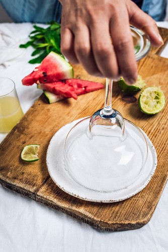 A woman dipping a margarita glass into salt