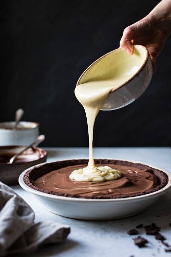 A chocolate pie base being filled with melted chocolate