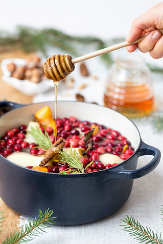 Honig wird auf pochierte Birnen mit Cranberries geträufelt