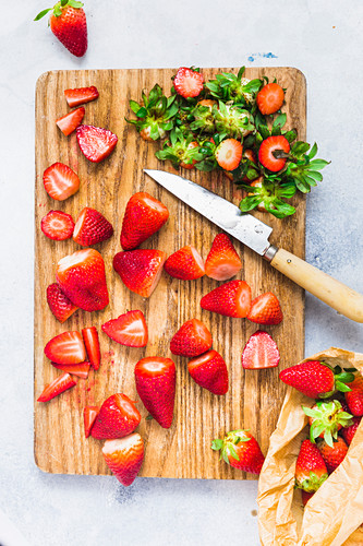 Strawberries on a wooden board, destemmed and sliced