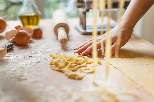 Cutting thin strips of pasta in hands while preparing meal in kitchen