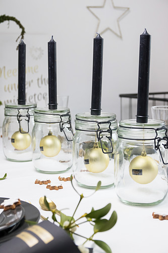 Black candles on mason jars with Christmas-tree baubles inside