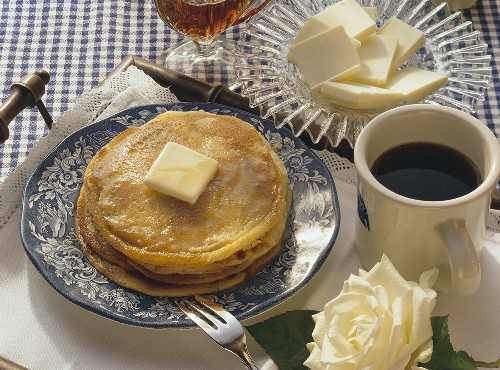 Pancakes mit Butter & Ahornsirup auf Teller & Tasse Kaffee