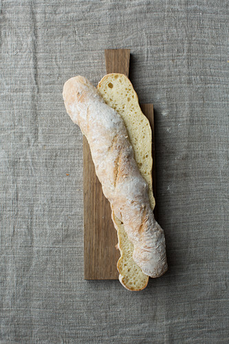 A light baguette, halved lengthways, on a wooden board