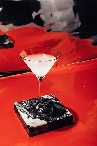 A margarita on a marble plate in front of a red background