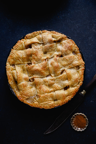 Apple pie with lattice decoration on dark background