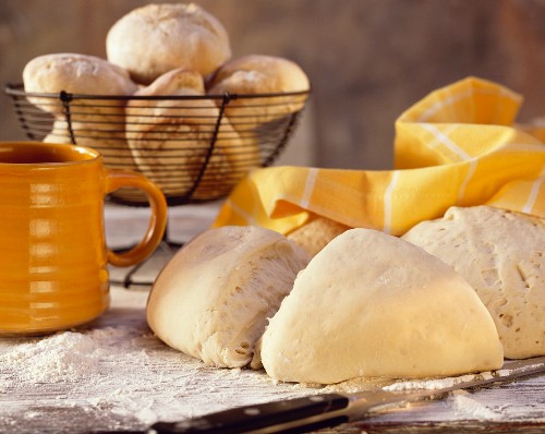 Backstilleben mit Hefeteig & hellen Brötchen auf Holztisch