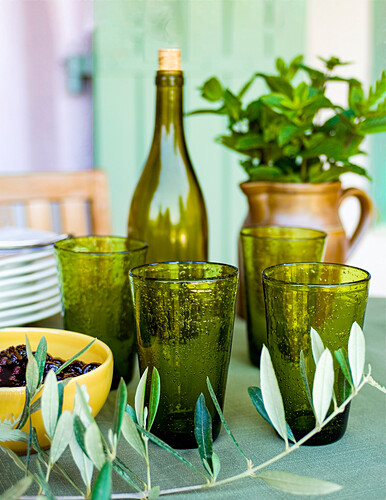 Green glasses, black olives in bowl, olive branch, in the background jug with mint