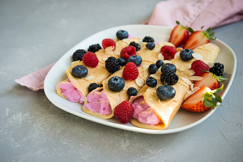 Food frame of assorted russian breakfast on white wooden table with copy  space. Pancakes (blini) with caviar, cottage cheese, honey, cereal, boiled  egg, coffee and milk. Stock Photo