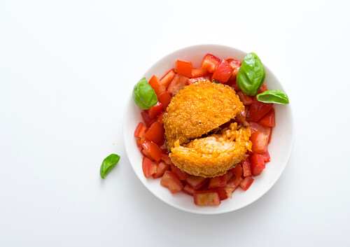 Suppli (Stuffed baked rice balls, Italy) on tomato salad