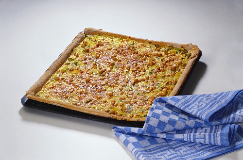 Leek and onion quiche with peanuts on baking tray