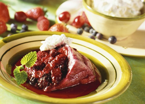 Berry pudding with cream on plate, ingredients behind