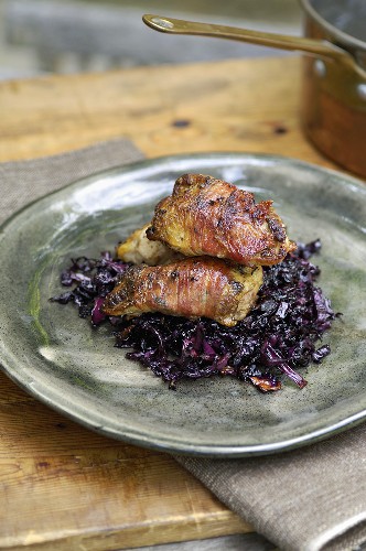 Roast partridge breasts wrapped in bacon on red cabbage
