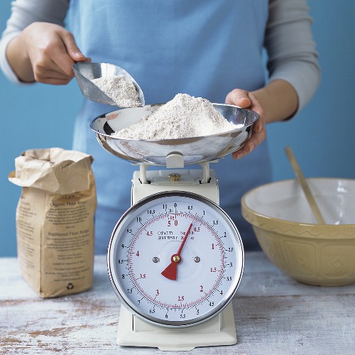 Woman weighing flour on scales – License Images – 330715 ❘ StockFood