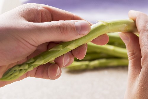 Das holzige Ende vom grünen Spargel abbrechen