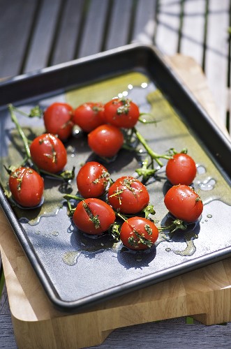 Tomaten mit Kräutern und Olivenöl auf einem Backblech